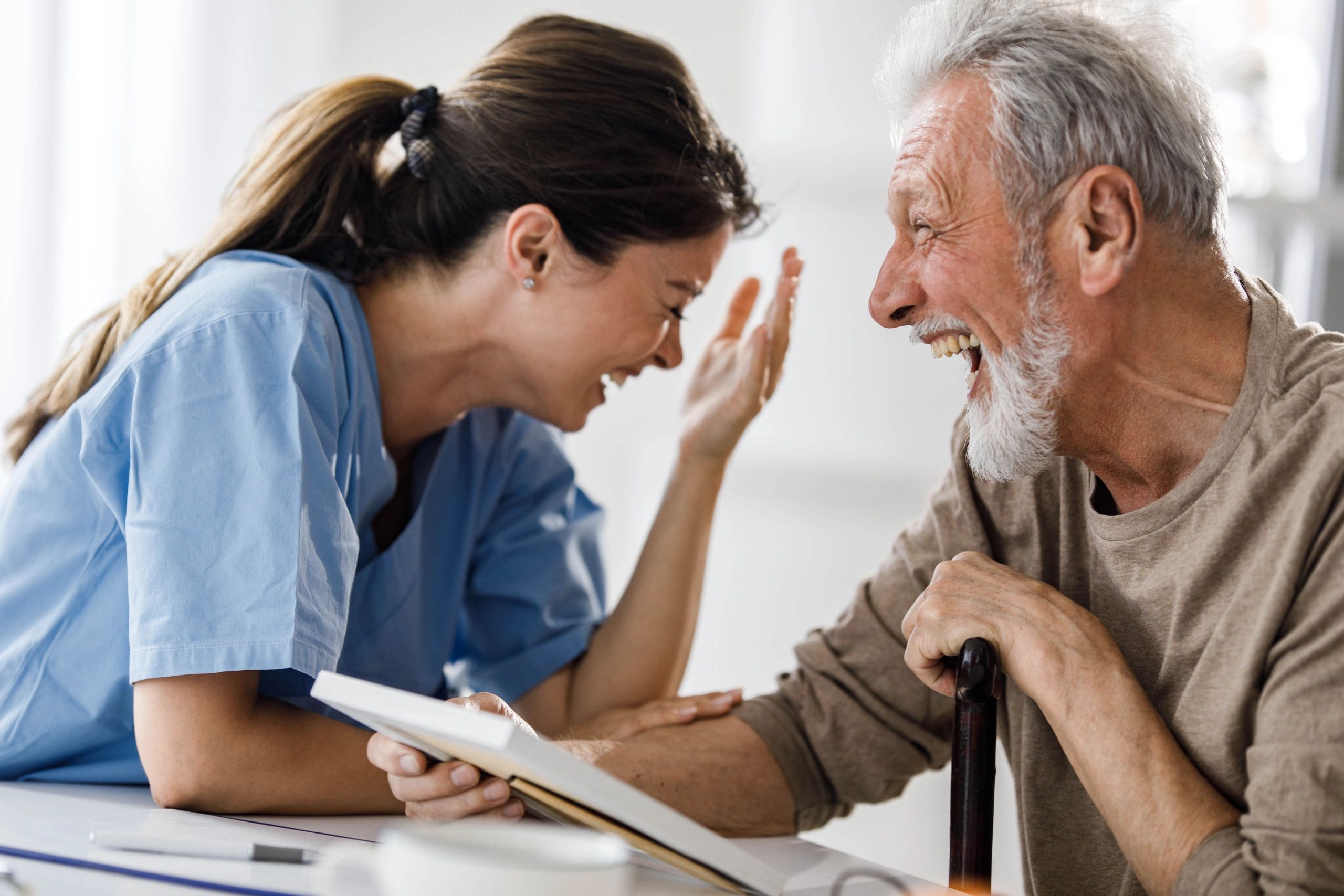 Nurse and senior client sharing a warm conversation during a home care visit